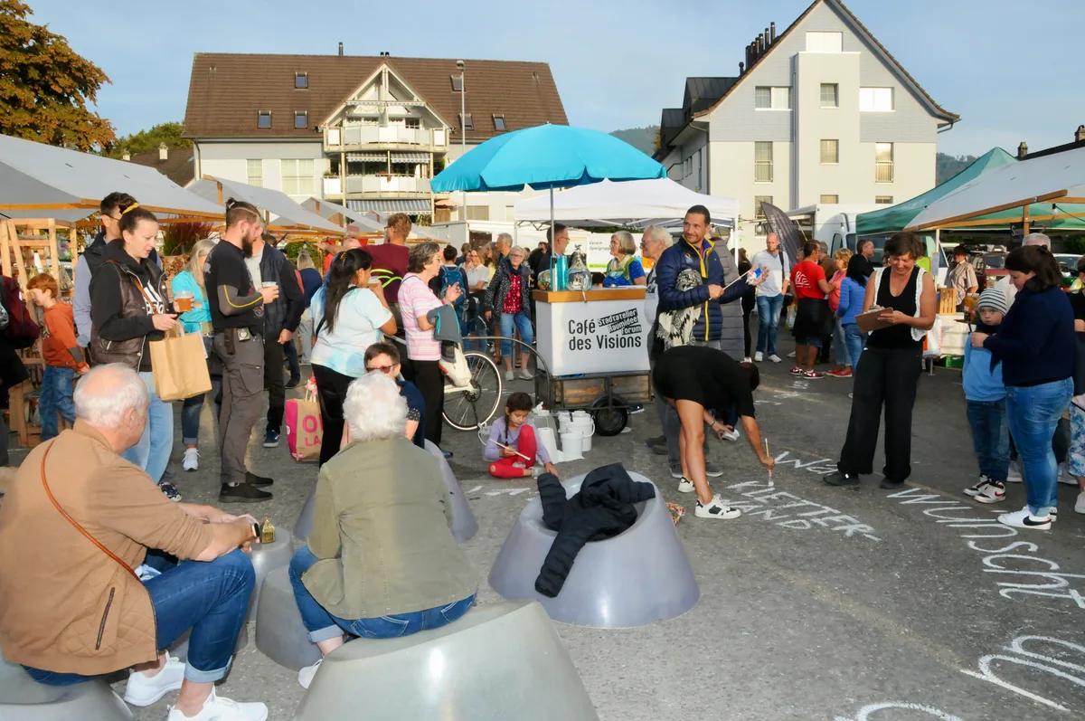 Menschen auf einem Platz. Ein Man malt auf den Boden. 